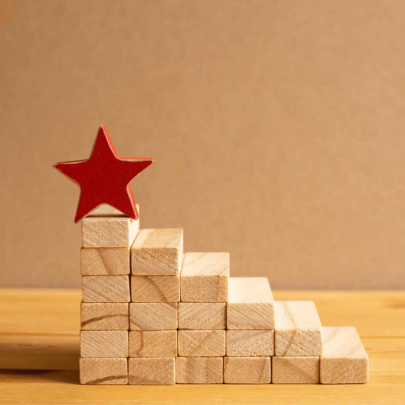 Photo shows the building blocks that look like stairs that reach toward a star at the top, representing how the steps to build a great compensation philosophy are chosen carefully and thoughtfully.